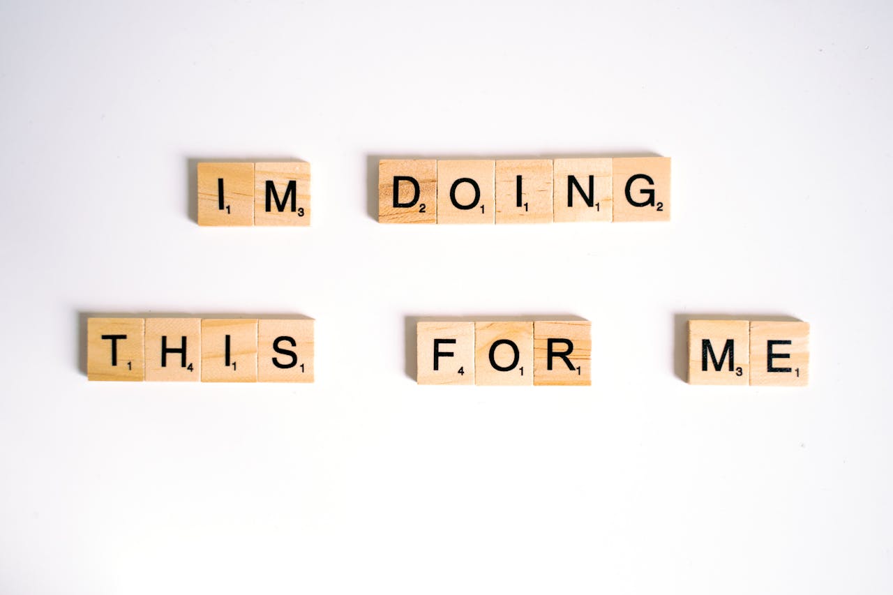 Wooden Scrabble tiles spell 'I'm doing this for me' on a white surface.